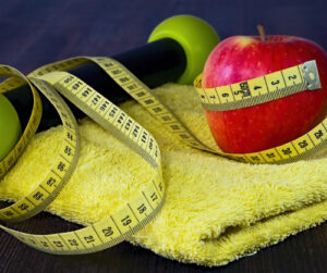 Weight, apple, and measuring tape sitting on a towel.